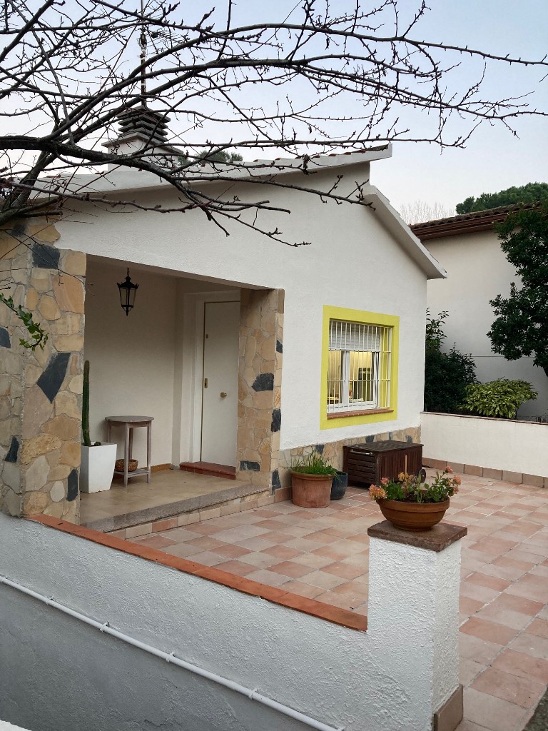 Fachada lateral con camino de baldosas, bajante y jardín, reforma integral La Floresta