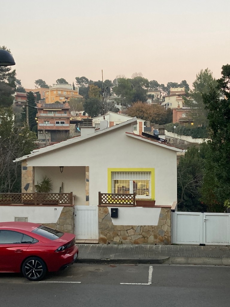 Vivienda unifamiliar en La Floresta vista desde la calle con fachada blanca y marcos de ventana amarillos