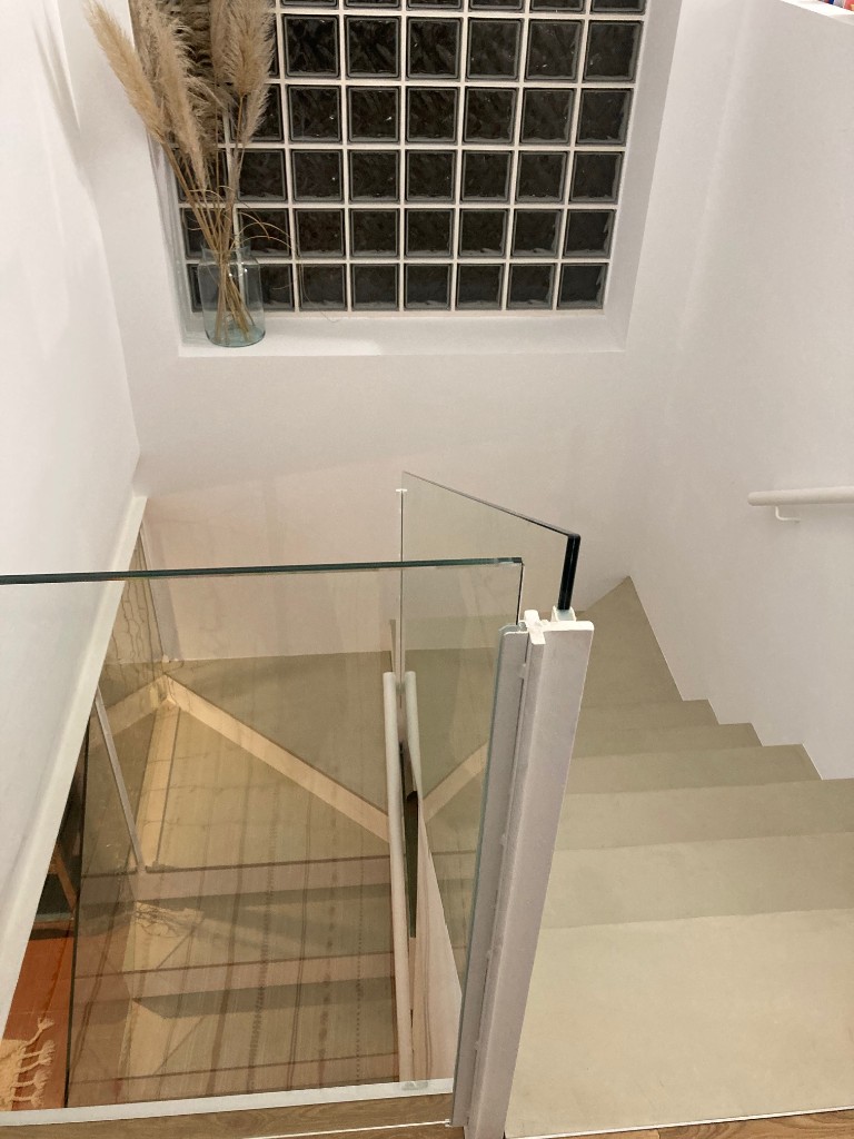 Escalera con ventanal de pavés de cristal y pasamanos blanco, diseño minimalista La Floresta